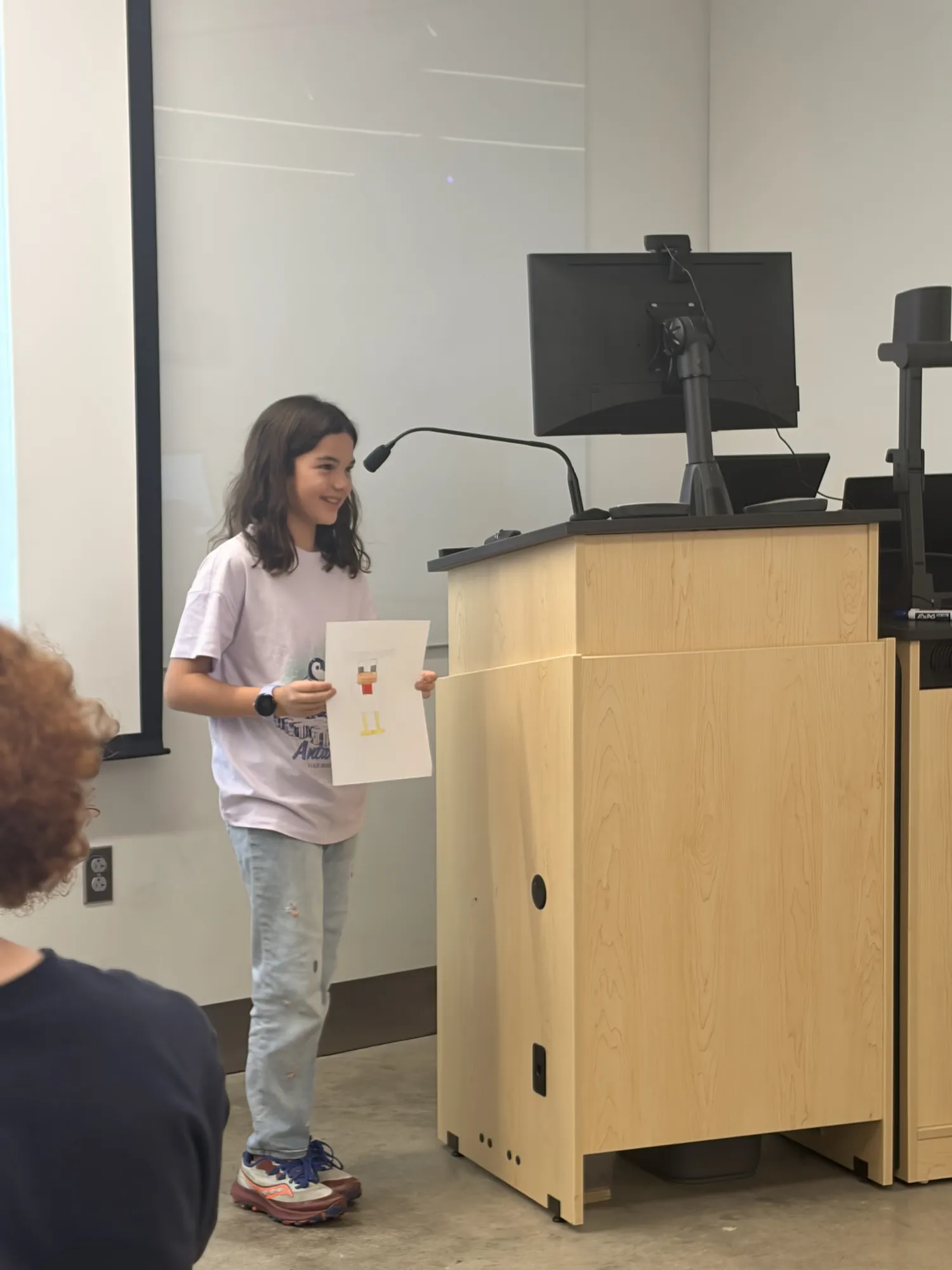 A student presents her drawing to the room